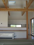 ２階のないＬＤＫの空間は、トステムＤＲＰパネルを採用して屋根裏の空間も取り込んで構造を現わすデザイン。カウンターの奥にキッチン。天窓は自然換気のための排気マドで電動開閉式。
